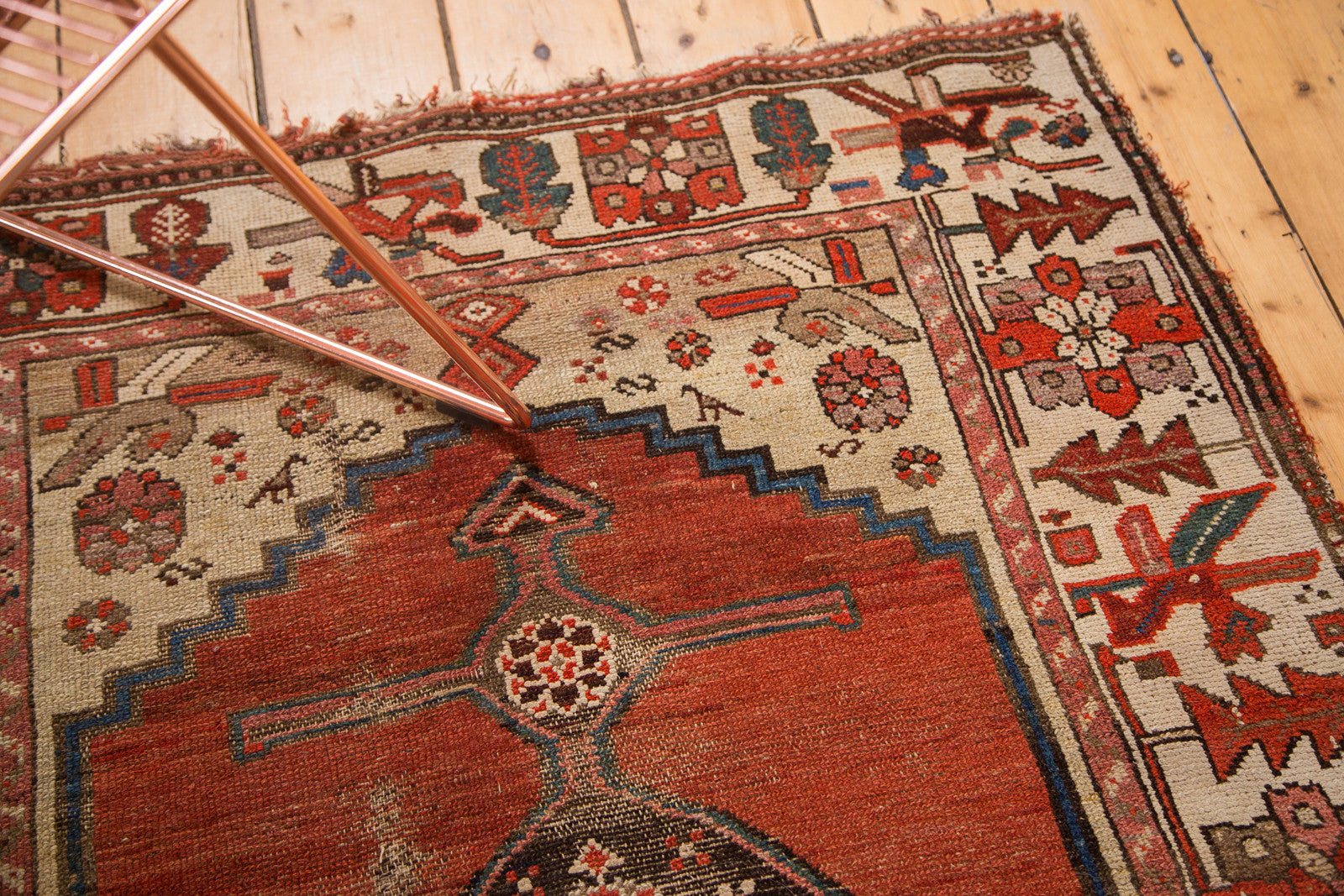 Worn Kurdish Hamadan rug corner, ivory spandrel, geometric bird motifs, red field.